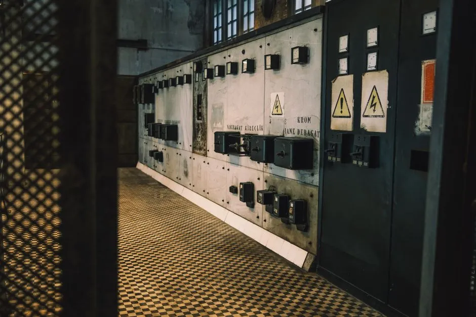 Industrial comms room showing a Moxa NPort serial device server cabled to a compact site PC running Sentinel Bridge — original nurse call panel and fire panel hardware untouched on the wall behind