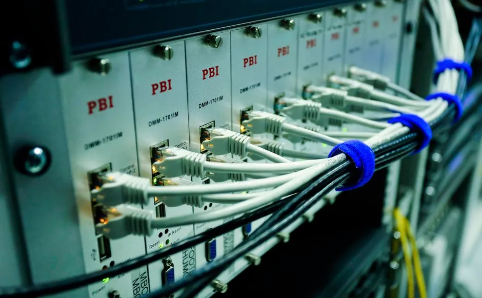 Close-up of a Moxa NPort serial-to-ethernet device connected to a rackmount panel in a building communications room